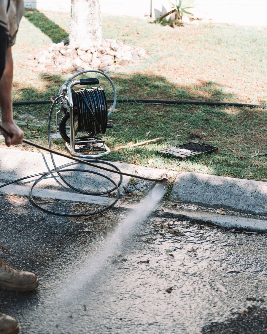 High-pressure jetter blasting water across a driveway